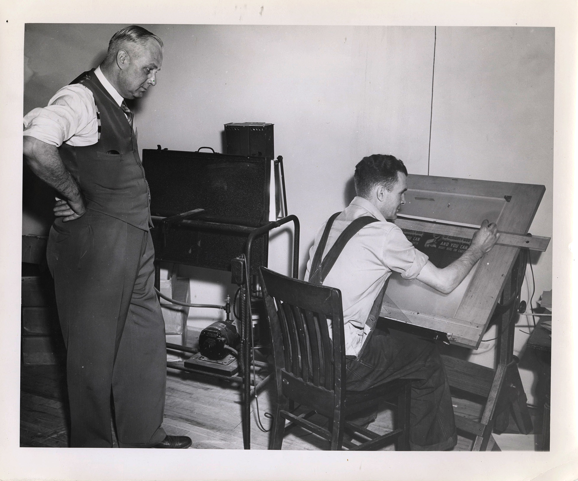 Photograph of Frank B. Robinson watching the work of an unidentified male staff member